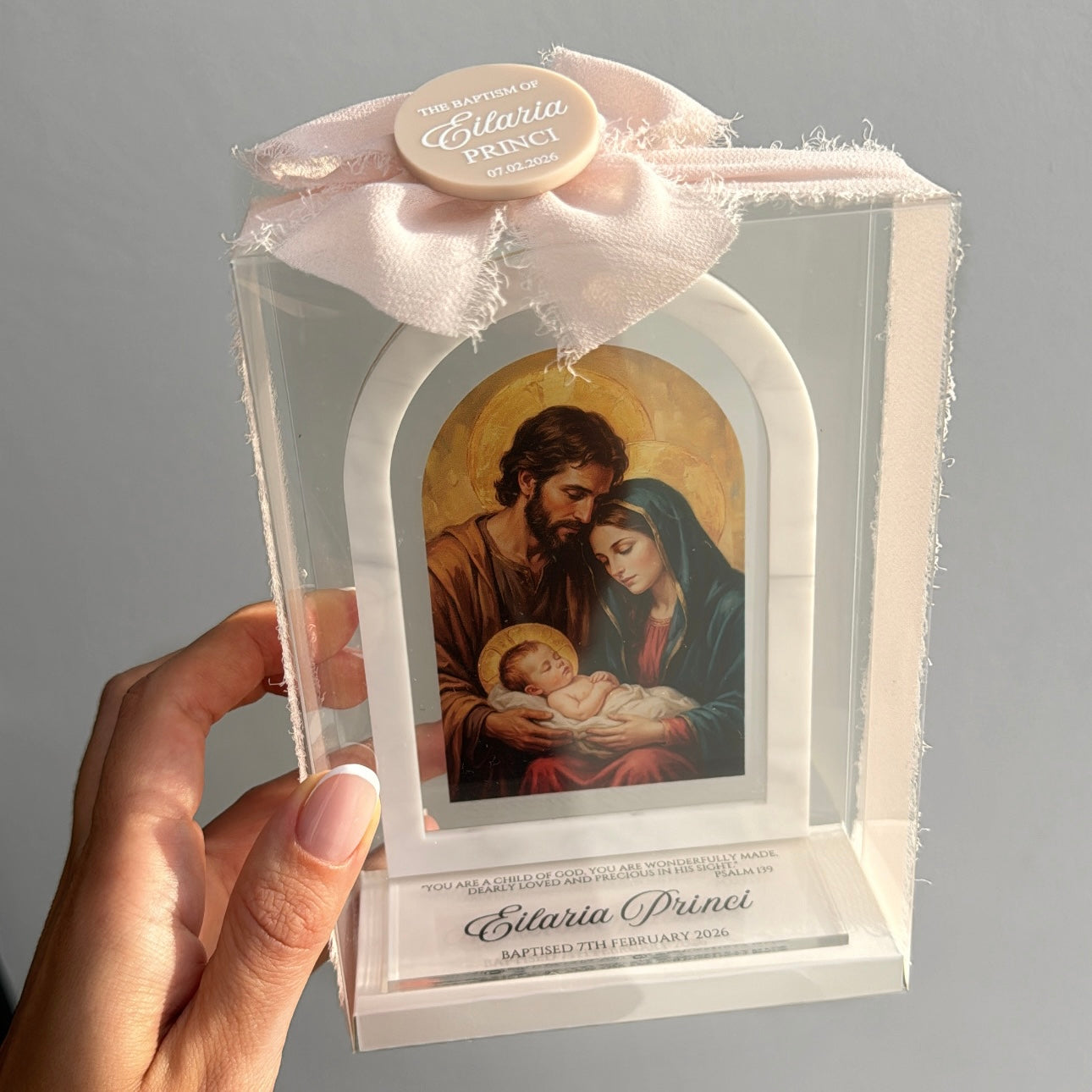 Acrylic arch plaque favour with a religious scene of a holy family holding a baby, personalised with child’s name 