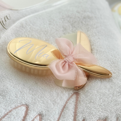 Gold personalised hairbrush with a pink bow on a white background - christening gift 
